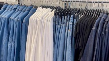 Akıllı gömlekler ve klasik tonda pantolonlar erkek giyim mağazasında ahşap bir duvara, hızlı moda konseptine, yavaş çekim fikrine karşı düzgünce asılıdır.