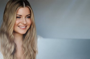 Laptop yaşam tarzı ve evden çalışma, internet kursu, bilgisayar kullanan uzun dalgalı saçlı sarışın kadın, doğal makyaj ve mavi gözler, dijital yaşam dengesi.