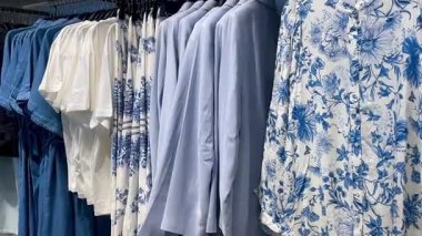 Butik elbise vitrinleri, ahşap askılar ve zarif tasarım, hızlı moda konsepti, yavaş çekim, ahşap raflarda desenli kadın modası sergileniyor.