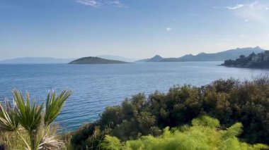 Türkiye 'nin Bodrum kenti yakınlarındaki Ege Denizi, ufuk boyunca uzanan adalar ve burunlar yemyeşil, yavaş çekim
