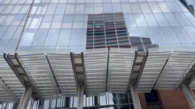 Londra 'daki Çömlek' in dramatik yükseliş manzarası, cam cephesi bulutlu gökyüzüne doğru inceliyor, modern İngiliz mimarisinin yüksekliğini ve zarafetini yakalıyor, yavaş çekim.