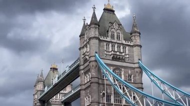 Londra 'daki Tower Bridge' in görkemli bir yakın görüntüsü, Thames Nehri 'nin üzerinde dramatik bulutların altında cesurca duruyor, değerli bir İngiliz ikonu, yavaş çekim