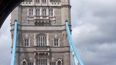 Londra 'daki Tower Bridge' in görkemli bir yakın görüntüsü, Thames Nehri 'nin üzerinde dramatik bulutların altında cesurca duruyor, değerli bir İngiliz ikonu, yavaş çekim
