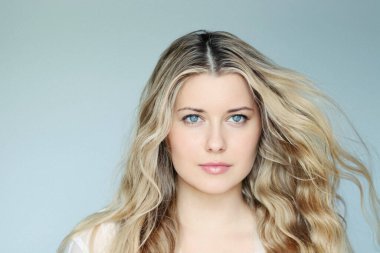 Natural beauty and hair care, blonde woman with blue eyes and elegant flowing waves, calm expression, light mint background
