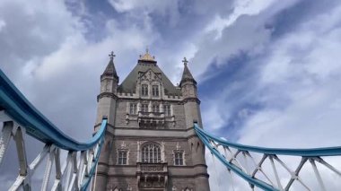 Londra 'daki Tower Bridge' in görkemli bir yakın görüntüsü, Thames Nehri 'nin üzerinde dramatik bulutların altında cesurca duruyor, değerli bir İngiliz ikonu, yavaş çekim