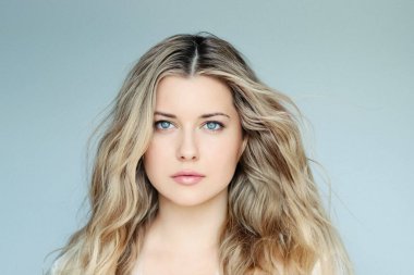 Natural beauty and hair care, blonde woman with blue eyes and elegant flowing waves, calm expression, light mint background