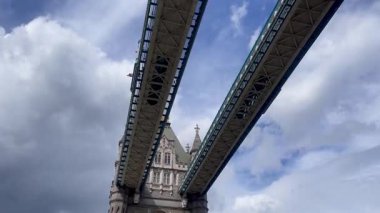Londra 'daki Tower Bridge' in görkemli bir yakın görüntüsü, Thames Nehri 'nin üzerinde dramatik bulutların altında cesurca duruyor, değerli bir İngiliz ikonu, yavaş çekim