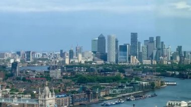 Londra 'nın modern nehir kenarı mimarisi ve Thames nehri boyunca gökdelenler, berrak mavi gökyüzü altında konut ve ticari binalar, yavaş çekim