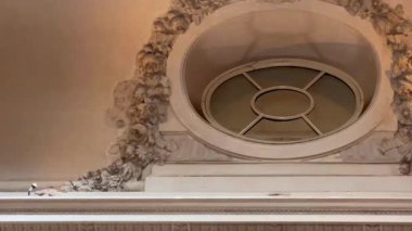 Süslü bir İngiliz tavanının, alçı kalıplı ve klasik simetriyle çerçevelenmiş dairesel bir havalandırma detayıyla yakın plan, yavaş çekim, kalıtım tlarıyla hafifçe aydınlatılmış.