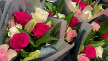 Çiçekçide sergilenen çiçekler, yumuşak kağıt buketlerde toplanmış taze yeşillik ve hassas tonlarda, yavaş çekim