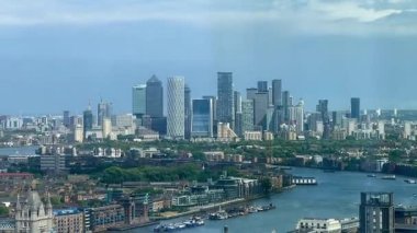 Londra 'nın modern nehir kenarı mimarisi ve Thames nehri boyunca gökdelenler, berrak mavi gökyüzü altında konut ve ticari binalar, yavaş çekim
