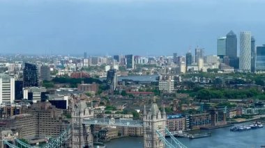 Londra 'nın modern nehir kenarı mimarisi ve Thames nehri boyunca gökdelenler, berrak mavi gökyüzü altında konut ve ticari binalar, yavaş çekim