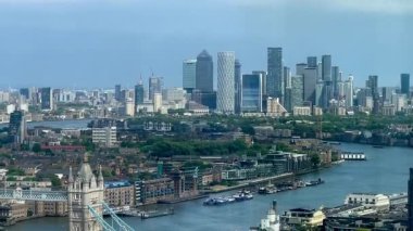 Londra 'nın modern nehir kenarı mimarisi ve Thames nehri boyunca gökdelenler, berrak mavi gökyüzü altında konut ve ticari binalar, yavaş çekim