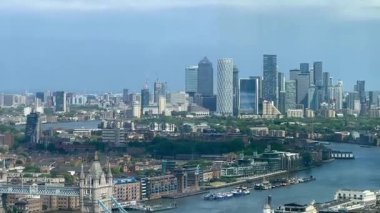Londra 'nın modern nehir kenarı mimarisi ve Thames nehri boyunca gökdelenler, berrak mavi gökyüzü altında konut ve ticari binalar, yavaş çekim
