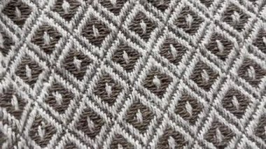 Yinelenen geometrik elmas desenli dokuma kumaş yüzeyinin yakın çekim görüntüsü, yumuşak çekimde doğal renk paleti