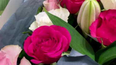 Çiçekçide sergilenen çiçekler, yumuşak kağıt buketlerde toplanmış taze yeşillik ve hassas tonlarda, yavaş çekim