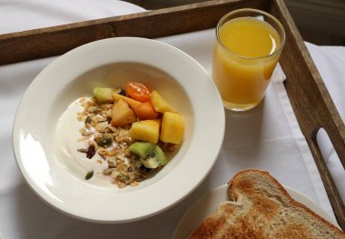Yoğurt, tahıl gevreği, taze meyve, portakal suyu ve yatakta tost ile sağlıklı bir kahvaltı servisi. Cotswold kırsal, İngiltere