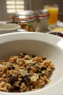 Breakfast bowl filled with crunchy granola, seeds, and dried fruit, ready to eat. Cotswolds countryside, England