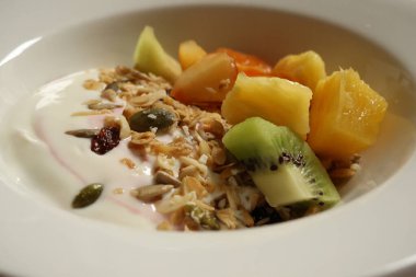 Healthy breakfast bowl with creamy yogurt, colorful fruit, crunchy granola, and mixed seeds. Cotswolds countryside, England