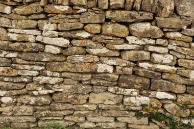 Düzensiz kayalarla kaplı kuru taş duvar yapısı doğal bir doku, arka plan ve yaşlanmış bir yüzey yaratıyor. Cotswolds, İngiltere