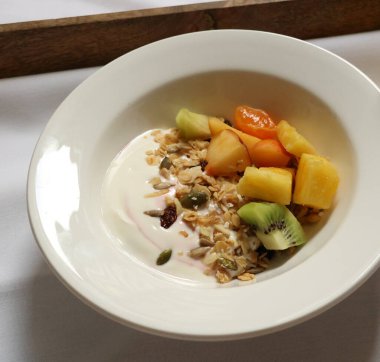 Yoğurt kasesi taze meyve ve tohumla granola sunuyor, sağlıklı bir kahvaltı sunuyor. Cotswold kırsal, İngiltere