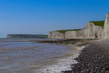 Seven Sisters chalk cliffs along the East Sussex coast, ocean waves breaking on a rocky beach, English landscape. East Sussex, England