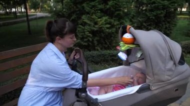 Panorama. Annem bebekle oynuyor. Küçük bir kız bebek arabasında yatıyor. 4K Ağır çekim