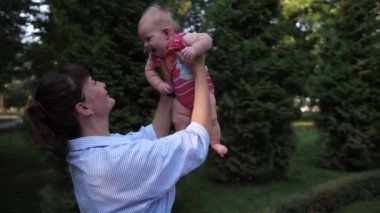 Anne kucağında bebek var. Küçük kız gülümsüyor. Annem onu öpüyor..