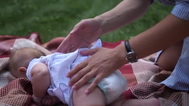 接近中だ 公園で無料の時間ながら小さなかわいい赤ちゃんの女の子をドレッシング若いお母さん Slow — ストック動画