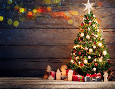 A charming Christmas tree adorned with bright ornaments and lights stands against a rustic wooden backdrop. Colorful presents and sparkling bokeh add a festive touch to this cozy holiday setting. clipart