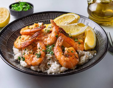 Dine on a vibrant seafood platter featuring succulent grilled shrimp atop fluffy greek rice, accompanied by tangy lemon wedges for a refreshing touch. Perfect for seafood enthusiasts. clipart