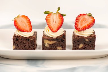Deliciously rich cake brownie slice with Chantilly cream and fresh strawberry.