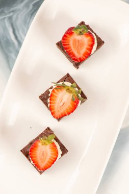 Deliciously rich cake brownie slice with Chantilly cream and fresh strawberry.