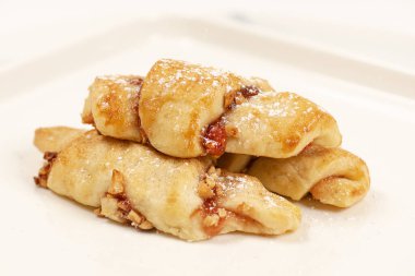 Rugelach cookies made on a cream cheese dough with strawberry jam, mixed nuts topped with cinnamon sugar. 