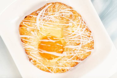 Fresh baked apricot and custard danish topped with white fondant and icing sugar.