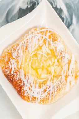 Fresh baked apple and custard danish topped with white fondant and icing sugar.