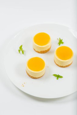Kremalı minyon mango peynirli kek, mango jölesi ve kepekli bisküvi kırıntısı..