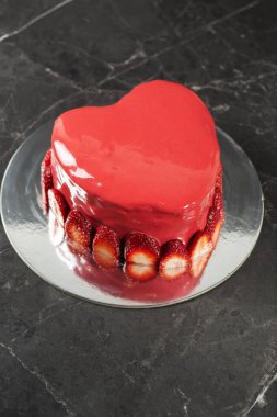 Gangache kaplamalı, kırmızı ayna jöleli güzel kalp şeklinde nemli çamur pasta ve taze çilek sınırı..