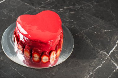 Gangache kaplamalı, kırmızı ayna jöleli güzel kalp şeklinde nemli çamur pasta ve taze çilek sınırı..