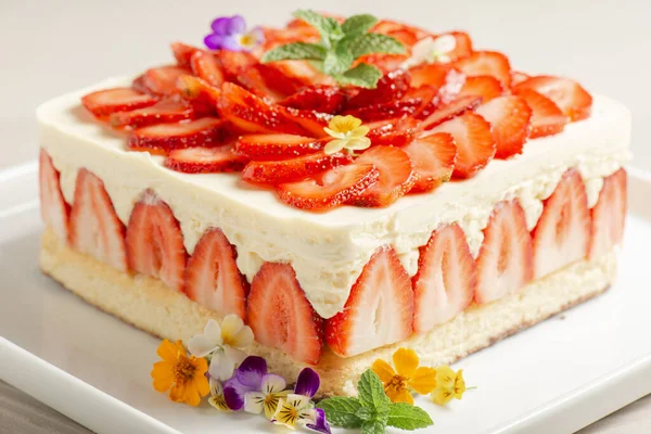 用热那亚海绵和外交乳霜装饰的美味的乳酪蛋糕 上面装饰着新鲜草莓和潘娜 图库图片