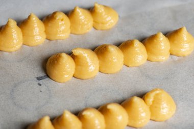 Sahne arkasında Paris-Brest ekler yapmak için pipoyla pişirilmemiş choux hamur işi mutfağındaki fotoğraf..