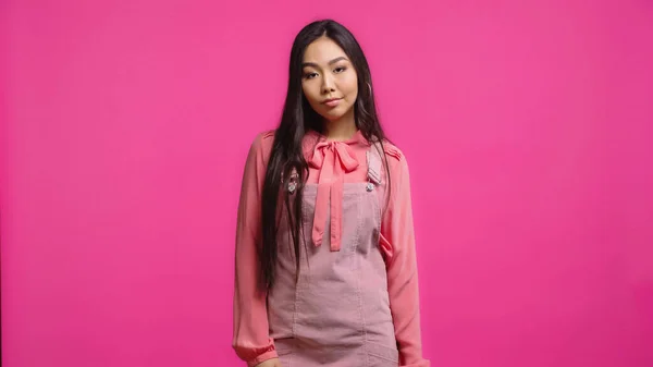 不满而年轻的亚洲女人看着被粉色隔离的相机 — 图库照片