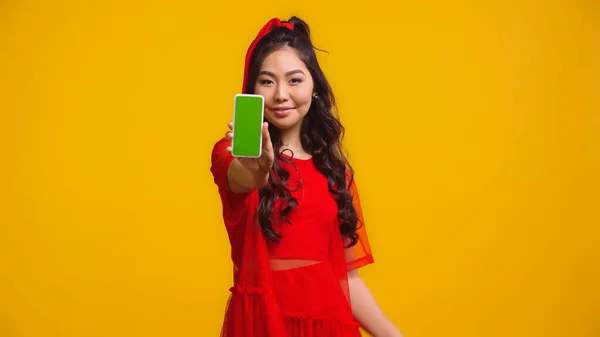 快乐的亚洲女人拿着智能手机 绿色屏幕与黄色隔离 — 图库照片