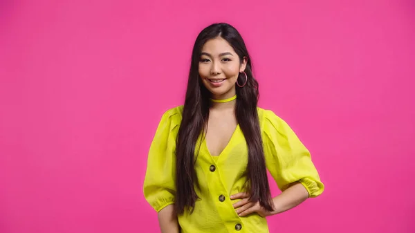 Stock image happy asian woman standing with hand on hip isolated on pink  