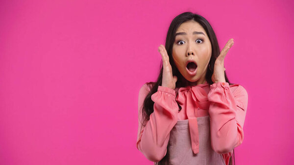 shocked and young asian woman with opened mouth gesturing isolated on pink