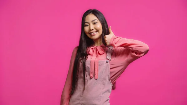 Feliz y morena asiático mujer mostrando pulgar arriba aislado en rosa - foto de stock