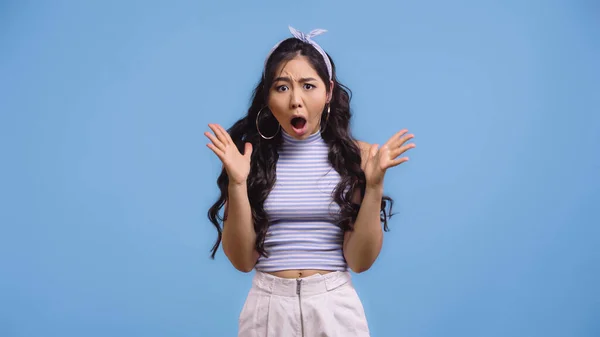 Impactado asiático mujer con abierto boca gesto aislado en azul - foto de stock