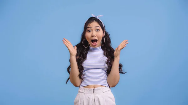 Espantado e jovem asiático mulher com aberto boca gestos isolado no azul — Fotografia de Stock