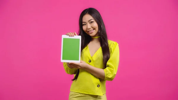 Счастливая азиатская женщина держит цифровой планшет с зеленым экраном изолированы на розовый — Stock Photo