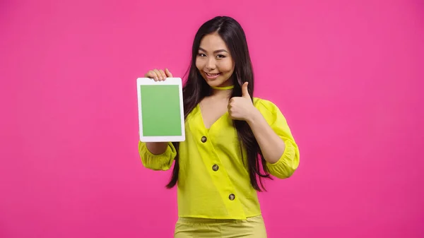 Happy asian woman holding digital tablet with green screen and showing like isolated on pink — Stock Photo